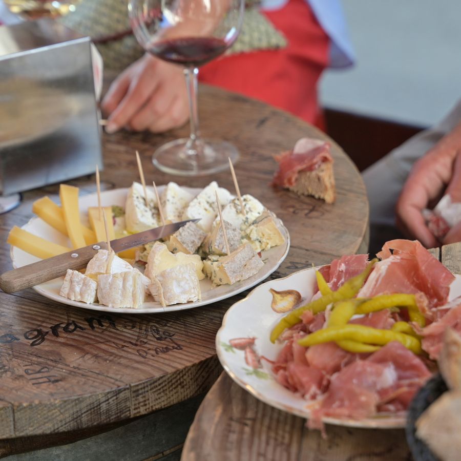 A board of French cheeses and charcuterie with a glass of wine